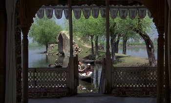 Movie still from “A Passage to India” (1984), directed by David Lean – Two people in a boat on a river; Extreme Wide shot, High angle