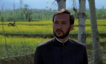 Movie still from “A Passage to India” (1984), directed by David Lean – A man with a beard is standing in front of a field; Close Up shot, Low angle