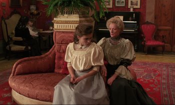 Movie still from “A Room with a View” (1985), directed by James Ivory – Two women sitting on a couch in a living room; Medium shot, High angle