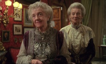 Movie still from “A Room with a View” (1985), directed by James Ivory – Two older women sitting next to each other in a room; Medium shot, Low angle