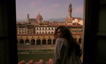 Movie still from “A Room with a View” (1985), directed by James Ivory – A woman standing on a balcony looking out at a city skyline; Medium shot, High angle