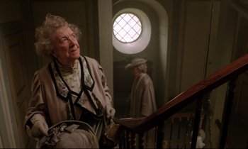 Movie still from “A Room with a View” (1985), directed by James Ivory – An older woman sitting on top of a set of stairs; Medium shot, Low angle