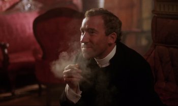 Movie still from “A Room with a View” (1985), directed by James Ivory – A man in a priest's outfit smoking a cigarette; Close Up shot, Low angle