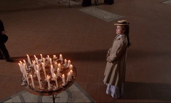 Movie still from “A Room with a View” (1985), directed by James Ivory – A woman standing in front of candles in a room; Wide shot, High angle
