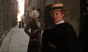 Movie still from “A Room with a View” (1985), directed by James Ivory – A woman in a hat is holding a briefcase; Medium shot, Low angle