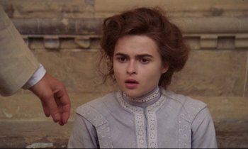 Movie still from “A Room with a View” (1985), directed by James Ivory – A young woman in a gray dress looking at the camera; Close Up shot, Over the shoulder angle