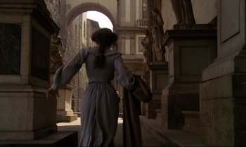 Movie still from “A Room with a View” (1985), directed by James Ivory – A woman walking down a street in a dress; Wide shot, Low angle