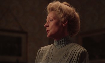 Movie still from “A Room with a View” (1985), directed by James Ivory – An older woman with blonde hair wearing a blue dress; Close Up shot, Low angle