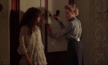 Movie still from “A Room with a View” (1985), directed by James Ivory – Two women in a room one of them is painting a door; Medium shot, Over the shoulder angle