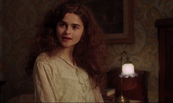Movie still from “A Room with a View” (1985), directed by James Ivory – A young woman with long hair standing next to a lamp; Close Up shot, Over the shoulder angle