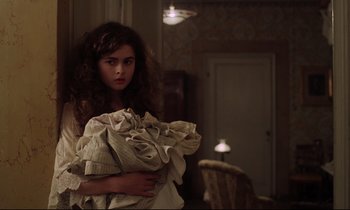 Movie still from “A Room with a View” (1985), directed by James Ivory – A young girl holding a bunch of newspapers in her arms; Medium shot, Low angle