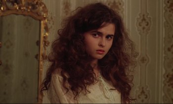 Movie still from “A Room with a View” (1985), directed by James Ivory – A young woman with long , curly hair posing for a picture; Close Up shot, Over the shoulder angle
