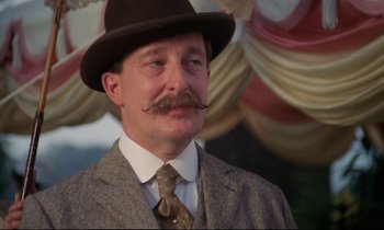 Movie still from “A Room with a View” (1985), directed by James Ivory – A man in a suit and a hat with a mustache; Close Up shot, Low angle