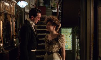 Movie still from “A Room with a View” (1985), directed by James Ivory – A man and a woman standing next to each other in front of a staircase; Medium shot, Low angle