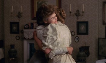 Movie still from “A Room with a View” (1985), directed by James Ivory – A woman hugging another woman in front of a fireplace; Medium shot, Over the shoulder angle