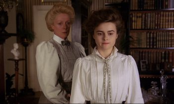 Movie still from “A Room with a View” (1985), directed by James Ivory – Two women dressed in victorian clothing standing next to each other in a room; Medium shot, Low angle