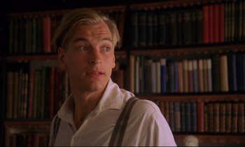 Movie still from “A Room with a View” (1985), directed by James Ivory – A man in white shirt standing in front of a book shelf; Close Up shot, Low angle