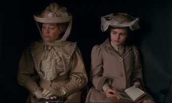 Movie still from “A Room with a View” (1985), directed by James Ivory – Two women dressed in period clothing sitting next to each other; Medium shot, High angle