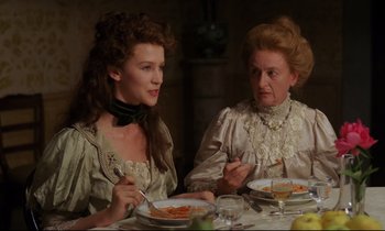 Movie still from “A Room with a View” (1985), directed by James Ivory – Two women sitting at a dinner table with plates of food in front of them; Medium shot, Over the shoulder angle