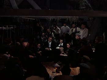 Movie still from “A Song to Remember” (1945), directed by Charles Vidor – A group of people sitting around a fire pit at night; Wide shot, High angle
