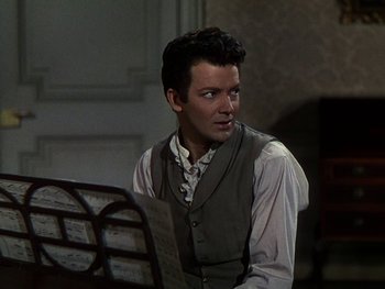 Movie still from “A Song to Remember” (1945), directed by Charles Vidor – A man sitting in front of a table holding papers; Medium shot, Over the shoulder angle