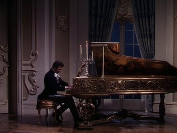 Movie still from “A Song to Remember” (1945), directed by Charles Vidor – A man sitting at a table playing a piano; Wide shot, High angle