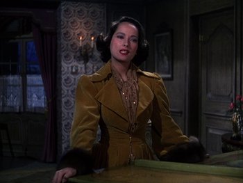 Movie still from “A Song to Remember” (1945), directed by Charles Vidor – A woman in a brown coat sitting at a table in a room; Medium shot, Over the shoulder angle