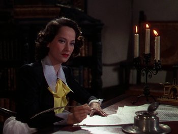 Movie still from “A Song to Remember” (1945), directed by Charles Vidor – A woman sitting at a table writing on a piece of paper; Medium shot, High angle