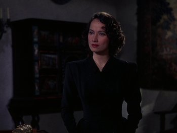 Movie still from “A Song to Remember” (1945), directed by Charles Vidor – A woman in a black dress standing in front of a table; Medium shot, Over the shoulder angle