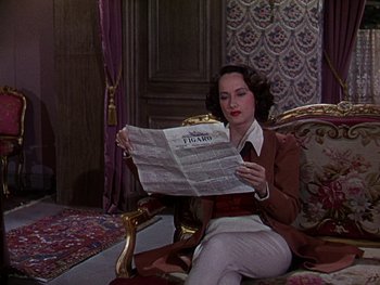 Movie still from “A Song to Remember” (1945), directed by Charles Vidor – A woman sitting on a couch reading a newspaper; Medium shot, High angle