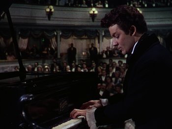 Movie still from “A Song to Remember” (1945), directed by Charles Vidor – A man in a black suit playing a piano in front of an audience; Medium shot, High angle