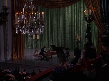Movie still from “A Song to Remember” (1945), directed by Charles Vidor – A man playing a piano in front of chandeliers; Extreme Wide shot, High angle