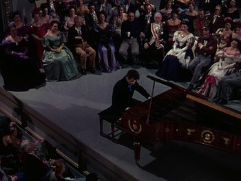 Movie still from “A Song to Remember” (1945), directed by Charles Vidor – A man playing a grand piano in front of a crowd of onlookers; Wide shot, High angle