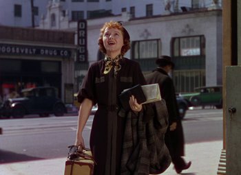 Movie still from “A Star Is Born” (1937), directed by Victor Fleming – An older woman walking down the street holding a suitcase; Medium shot, Low angle