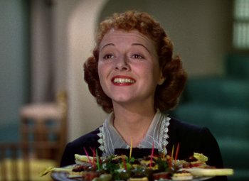 Movie still from “A Star Is Born” (1937), directed by Victor Fleming – A woman smiles while holding a plate of food in front of her face; Close Up shot, High angle