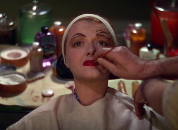 Movie still from “A Star Is Born” (1937), directed by Victor Fleming – A woman is getting makeup applied to her face; Close Up shot, Over the shoulder angle