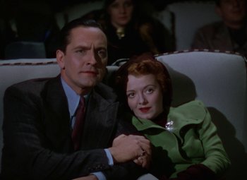 Movie still from “A Star Is Born” (1937), directed by Victor Fleming – A man and a woman sitting on a couch holding hands; Medium shot, Low angle