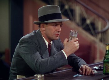 Movie still from “A Star Is Born” (1937), directed by Victor Fleming – A man wearing a hat and holding a glass of water; Medium shot, Low angle