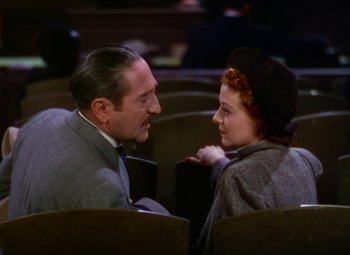 Movie still from “A Star Is Born” (1937), directed by Victor Fleming – An older man sitting next to an older woman in an auditorium; Medium shot, High angle