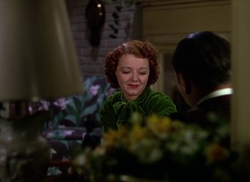 Movie still from “A Star Is Born” (1937), directed by Victor Fleming – A woman sitting at a table in a green dress; Medium shot, Over the shoulder angle