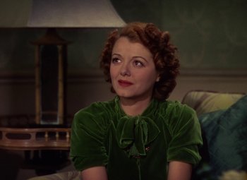 Movie still from “A Star Is Born” (1937), directed by Victor Fleming – A woman sitting on a couch wearing a green dress; Close Up shot, High angle