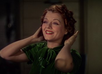Movie still from “A Star Is Born” (1937), directed by Victor Fleming – A woman in a green dress holding her hands up to her ears; Close Up shot, High angle