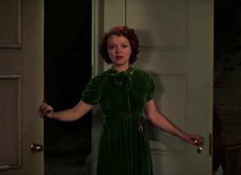 Movie still from “A Star Is Born” (1937), directed by Victor Fleming – A woman in a green dress standing in front of a door; Medium shot, High angle