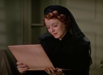 Movie still from “A Star Is Born” (1937), directed by Victor Fleming – A woman in a black dress holding a paper and a pen; Close Up shot, Low angle