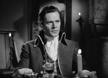 Movie still from “A Tale of Two Cities” (1935), directed by Jack Conway – A black and white photo of a man sitting at a dinner table; Medium shot, High angle