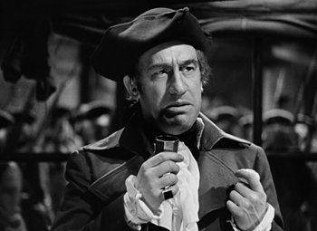 Movie still from “A Tale of Two Cities” (1935), directed by Jack Conway – A man in a hat and a coat holding a wine glass; Close Up shot, Over the shoulder angle