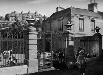 Movie still from “A Tale of Two Cities” (1935), directed by Jack Conway – A black - and - white photo of people walking in front of an iron gate; Extreme Wide shot, High angle