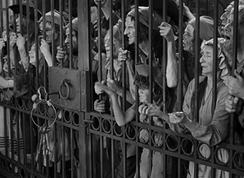 Movie still from “A Tale of Two Cities” (1935), directed by Jack Conway – A black and white photo of a group of people behind bars; Wide shot, High angle