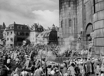 Movie still from “A Tale of Two Cities” (1935), directed by Jack Conway – A crowd of people standing around a large building; Extreme Wide shot, High angle
