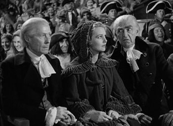 Movie still from “A Tale of Two Cities” (1935), directed by Jack Conway – A group of people sitting next to each other in a crowd; Medium shot, Over the shoulder angle